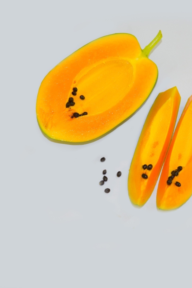 Разрезанная папайя на сером фоне
