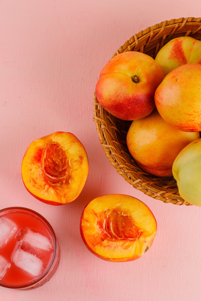 Свежий нектарин в корзине на розовом столе