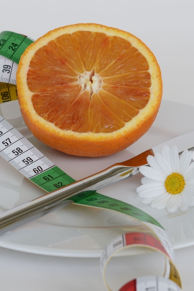 Половина апельсина на тарелке с сантиметром