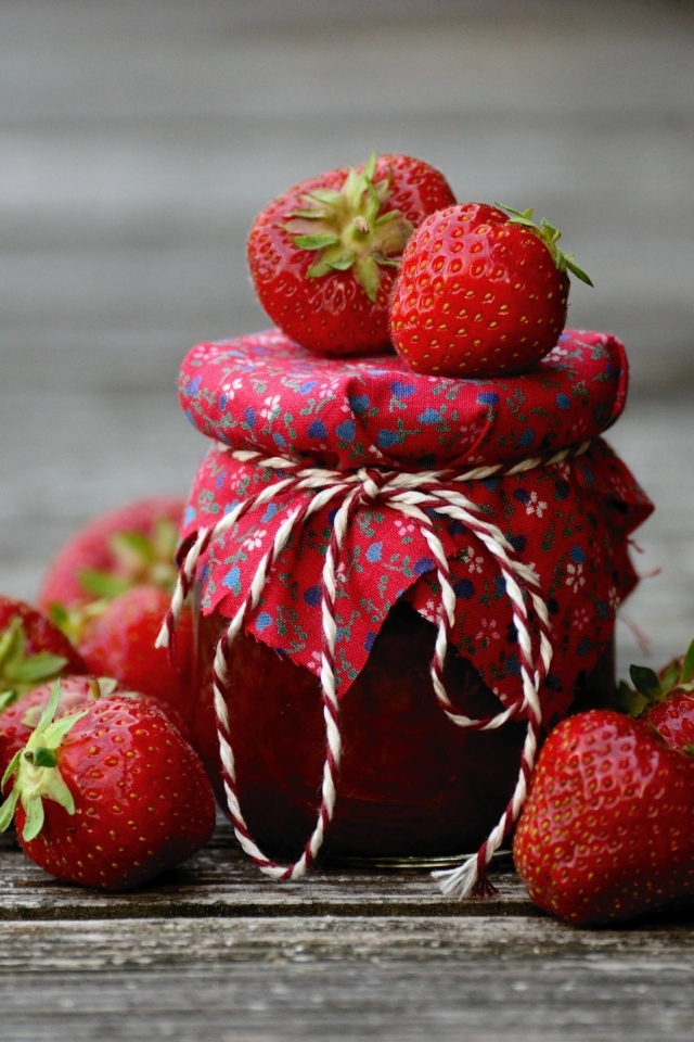 Банка джема на столе со свежими ароматными ягодами клубники