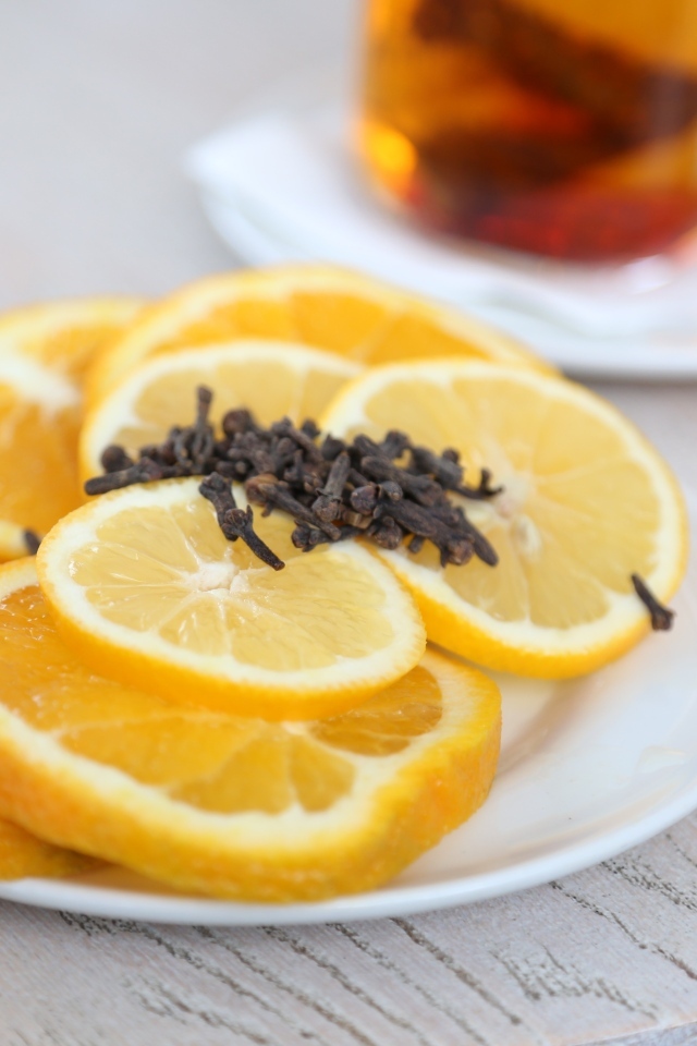 Лимон и апельсин с гвоздикой на тарелке