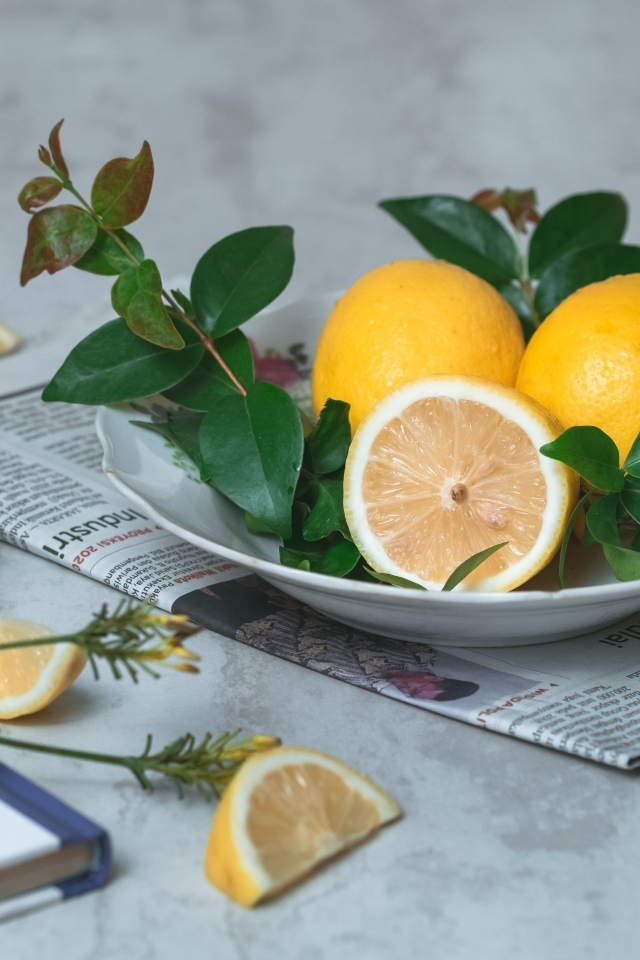 Лимоны на тарелке с зелеными листьями