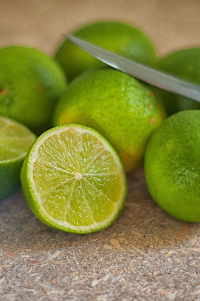 Много зеленых лаймов на столе с ножом