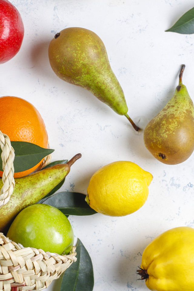 Груши, яблоки и апельсины с сумкой на столе