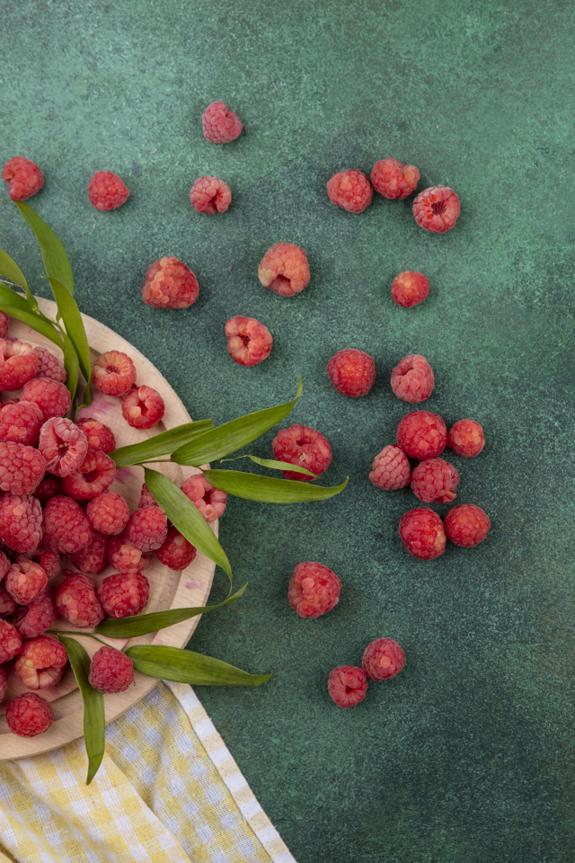 Красная малина с зеленой листвой на столе