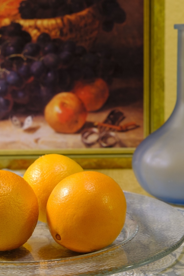 Три апельсина с вазами на столе