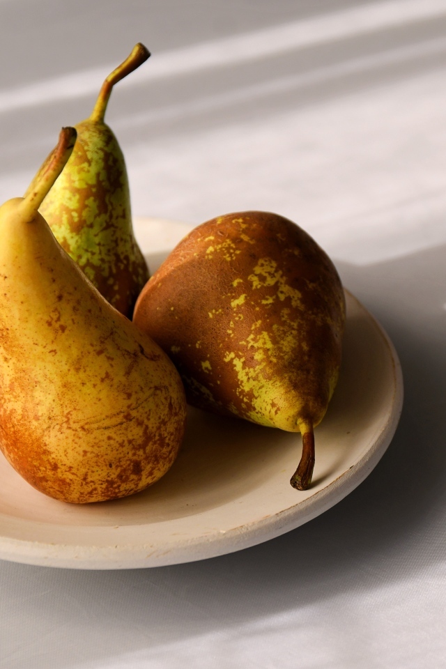 Три груши на тарелке на столе