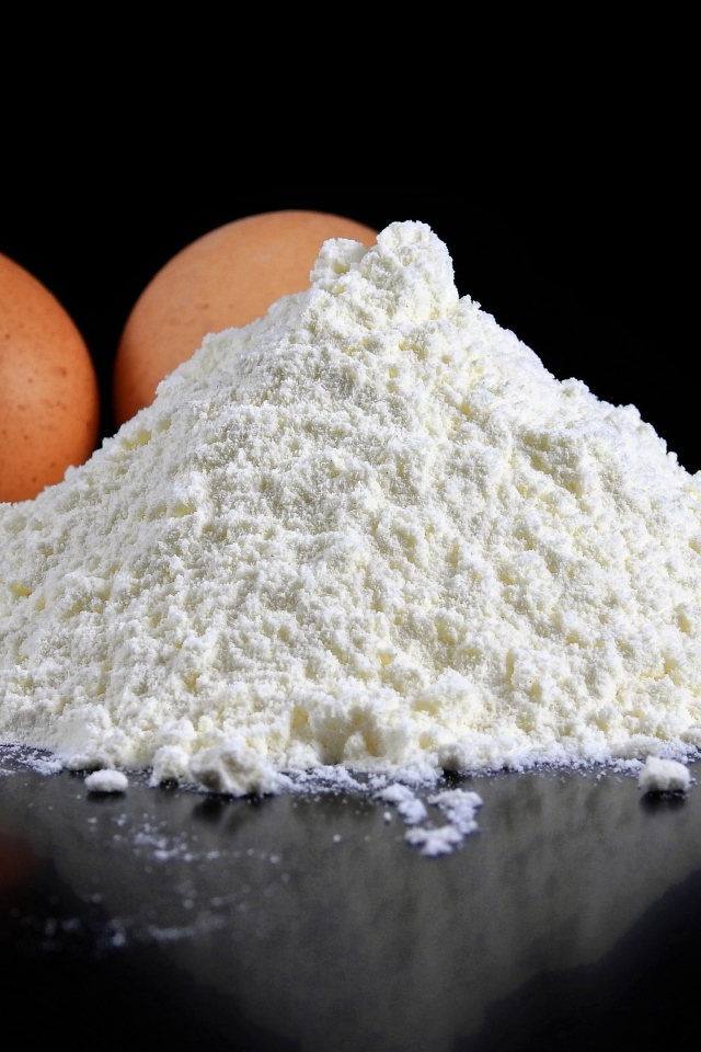 Мука на черном столе с куриными яйцами