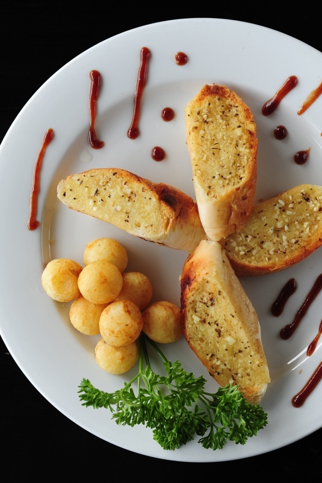 Чесночный хлеб на тарелке с картофельными шариками