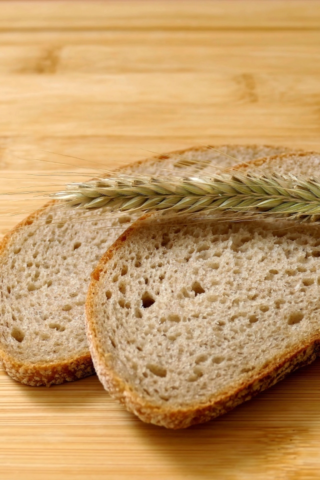 Два куска хлеба с колоском на деревянном столе