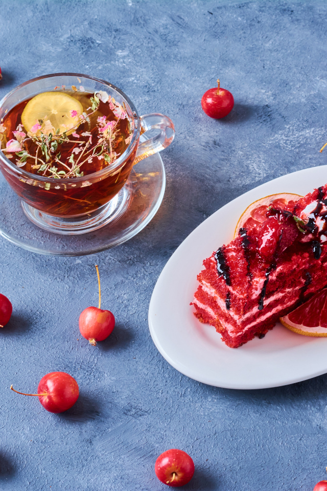 Аппетитный кусок торта на столе с чаем и ягодами черешни