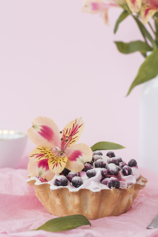 Черничное пирожное с цветами альстромерии на розовом фоне
