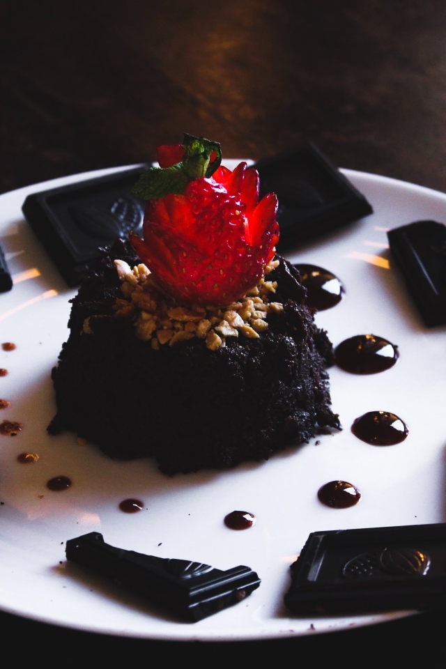 Десерт брауни на большой белой тарелке с шоколадом