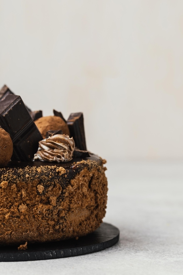 Торт украшен шоколадной глазурью и конфетами на сером фоне