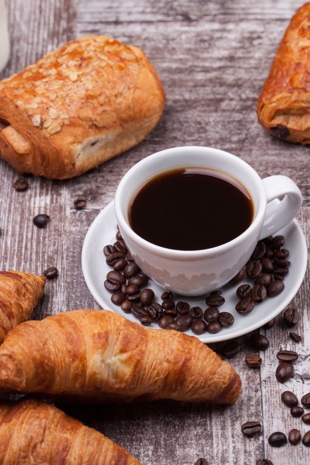 Кофе на столе с круассанами и зернами