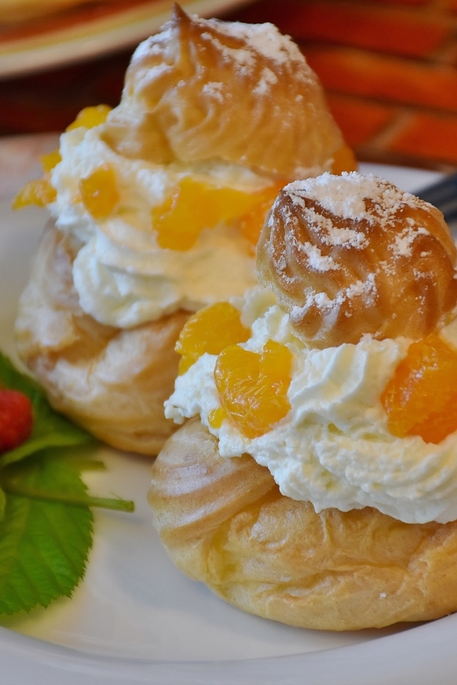 Заварное печенье со взбитыми сливками на тарелке с ягодами