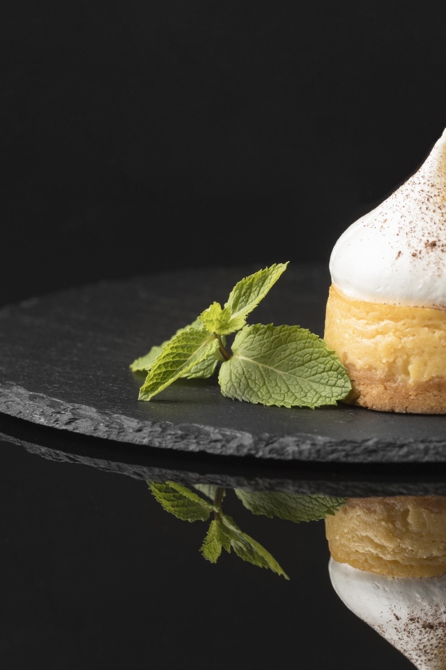 Десерт с кремом и листьями мяты на черном фоне