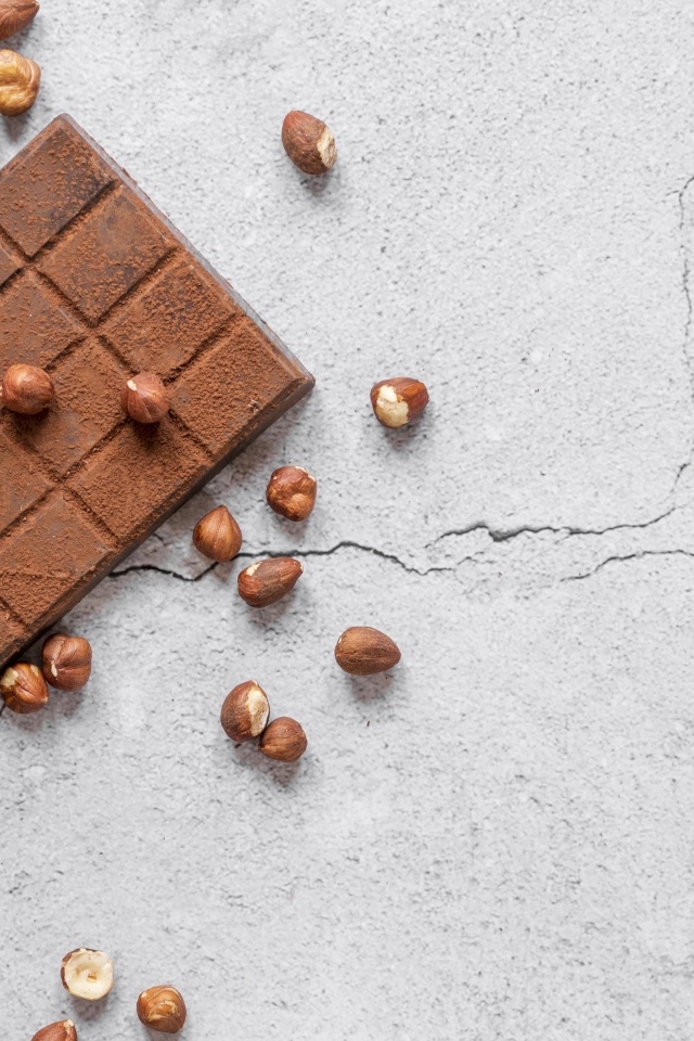 Молочная шоколадка с орехами на сером столе
