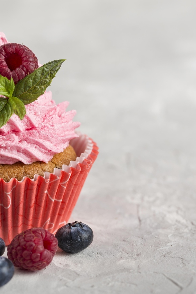 Маффин с розовым кремом и ягодами на столе
