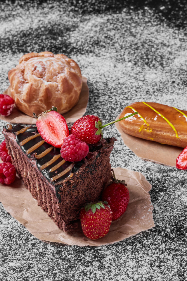 Кусок торта с ягодами на столе с эклером