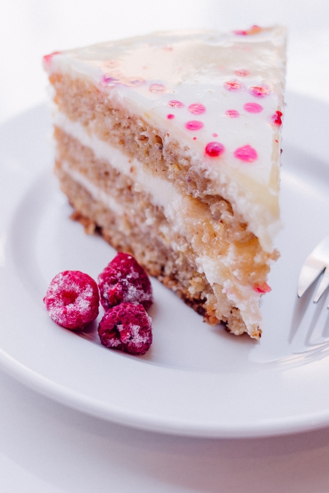 Кусок торта с замороженной малиной на белой тарелке