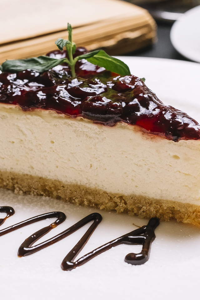 Кусок чизкейка с джемом на белой тарелке