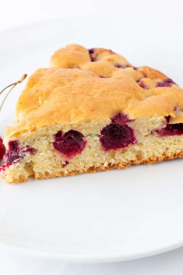 Кусок вишневого пирога с ягодами на тарелке