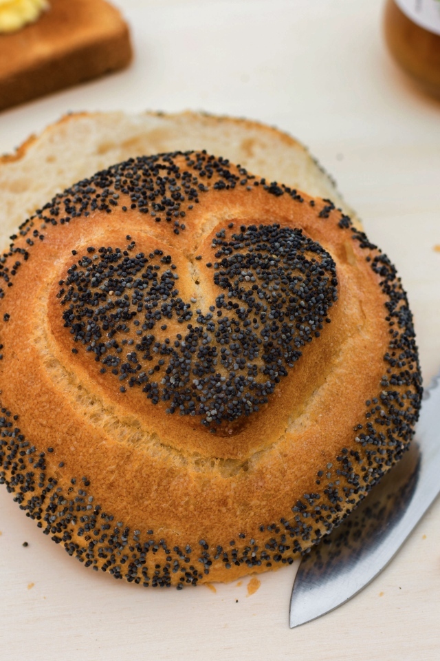 Булочка с маком с нарисованным сердцем на столе