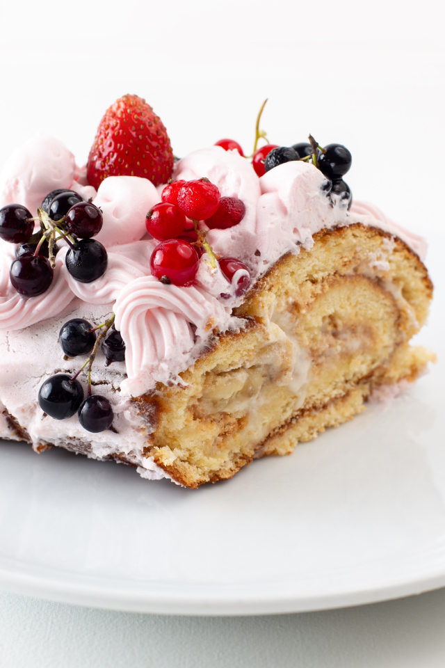 Ломтик сладкого рулета с ягодами и кремом