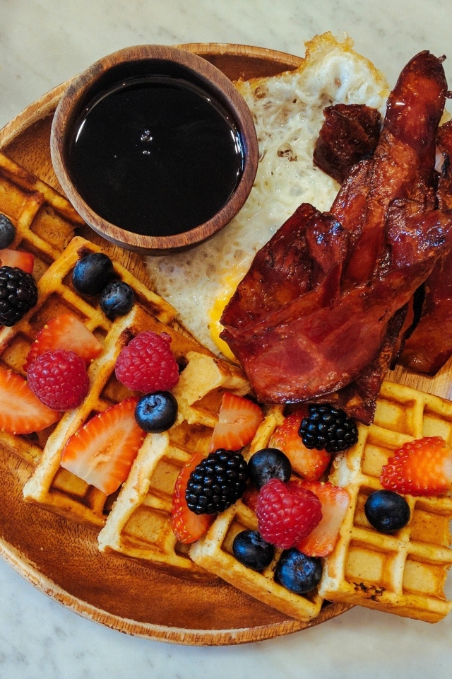 Сладкие вафли с ягодами на тарелке с беконом