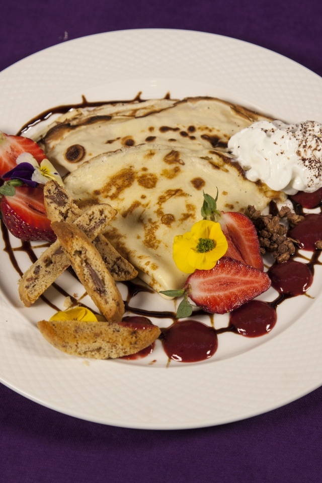 Тонкие блинчики с кремом и ягодами на тарелке