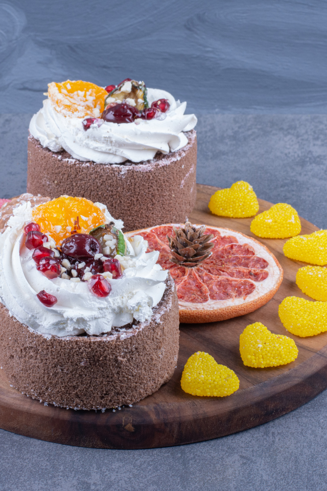 Два пирожных на деревянной доске с мармеладными конфетами