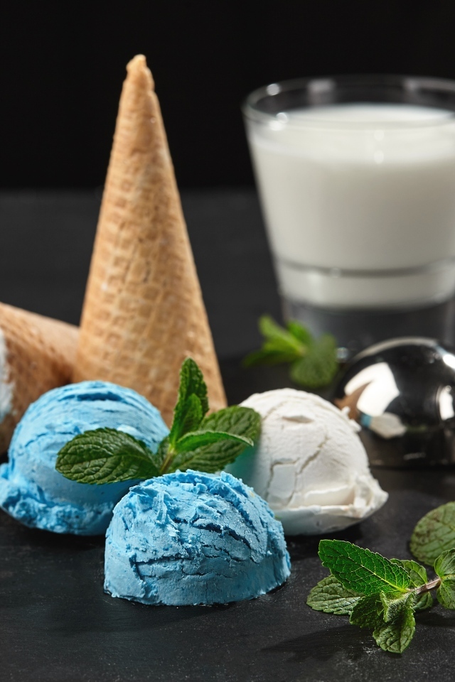 Вафельный рожок с шариками мороженого, мятой и молоком на столе