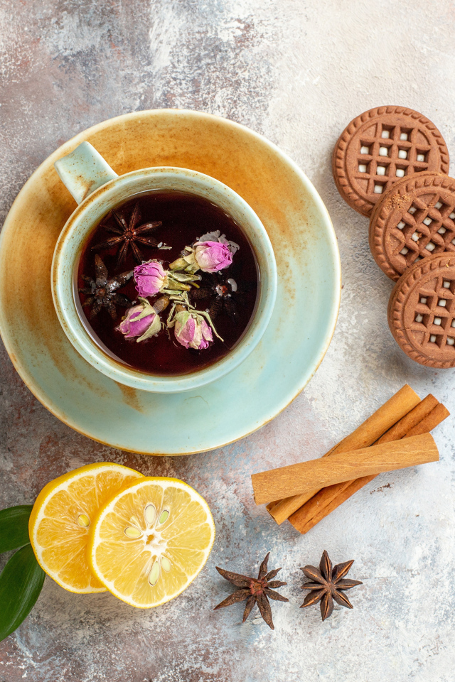 Чашка ароматного чая на столе с лимоном, печеньем и пряностями