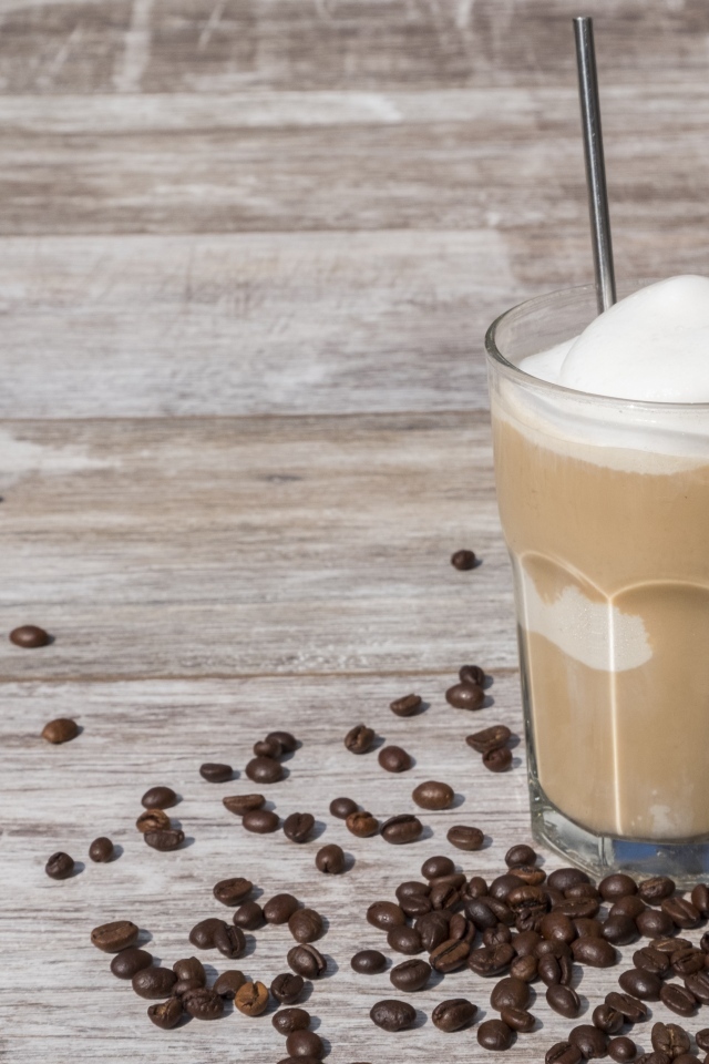 Кофе с мороженым в стакане на столе с кофейными зернами