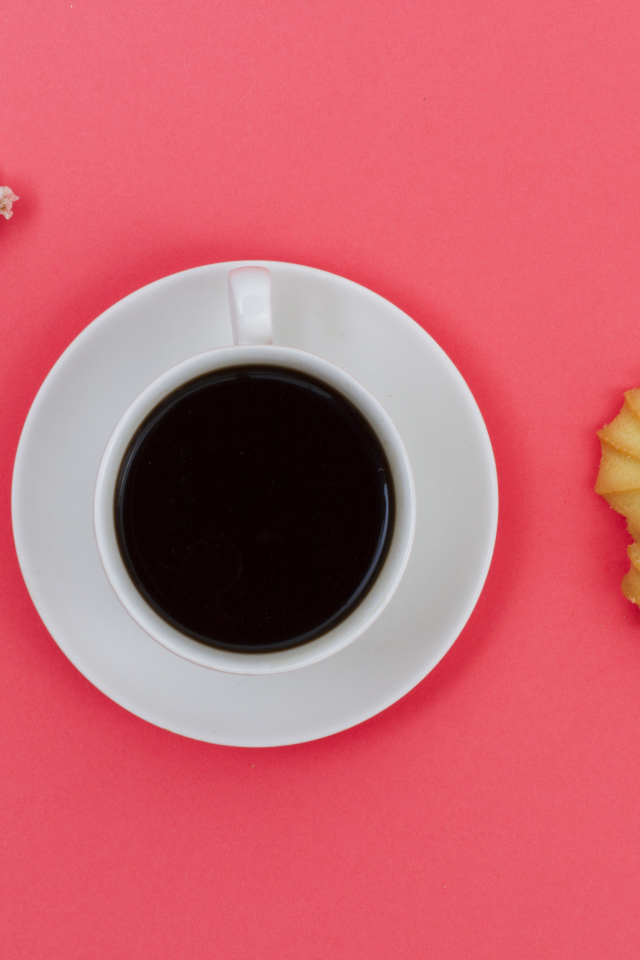 Чашка кофе на розовом фоне с цветком и печеньем