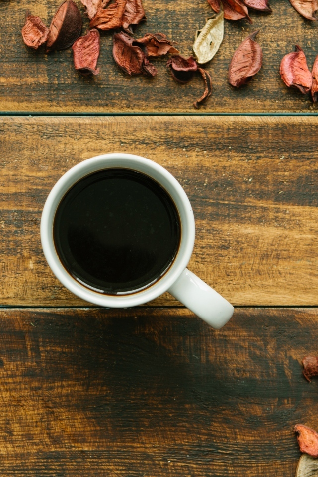 Чашка кофе с опавшими листьями на деревянном столе