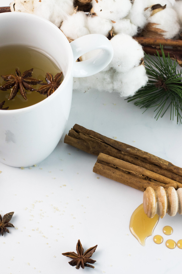 Чашка чая со специями на столе с хлопком и шишками