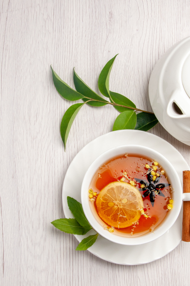 Вкусный чай в белой чашке на столе с лимоном и чайником