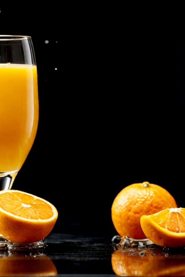 Стакан апельсинового сока с фруктами на столе