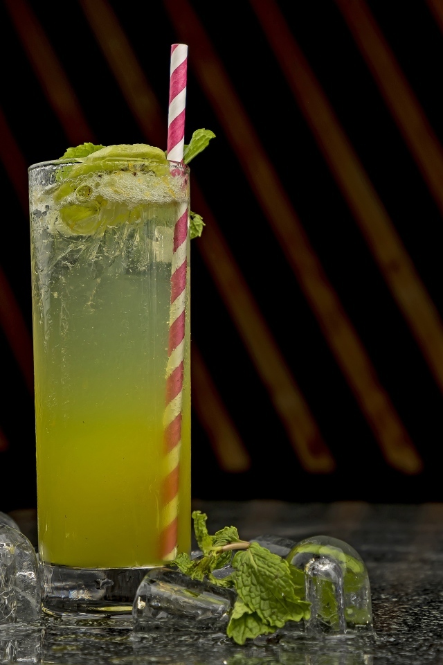 Зеленый коктейль мохито в высоком стакане со льдом