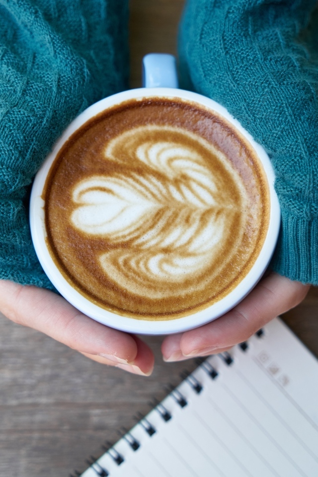 Горячая чашка кофе на столе в руках девушки