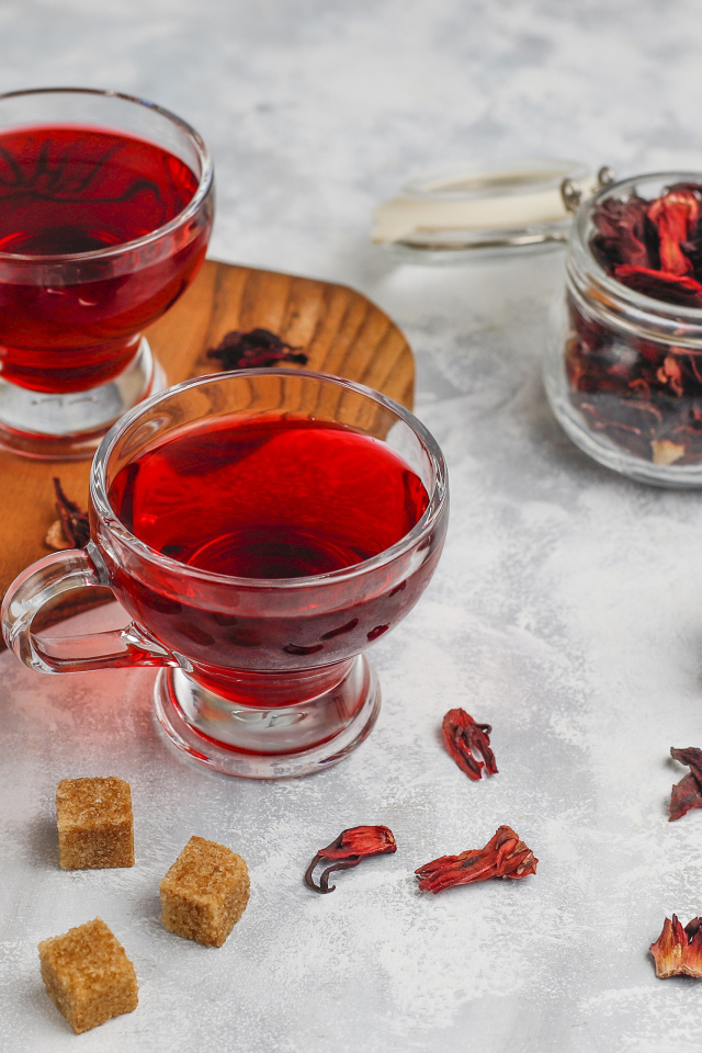 Две чашки чая каркаде на столе с заваркой 