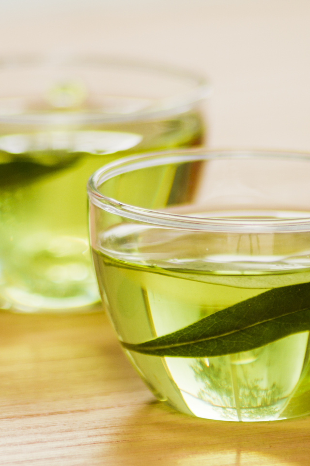 Две кружки зеленого чая с листьями