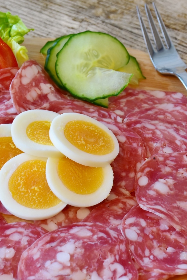 Колбаса салями на доске с вареными яйцами и овощами