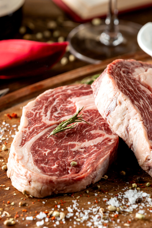 Два куска аппетитного стейка на столе со специями