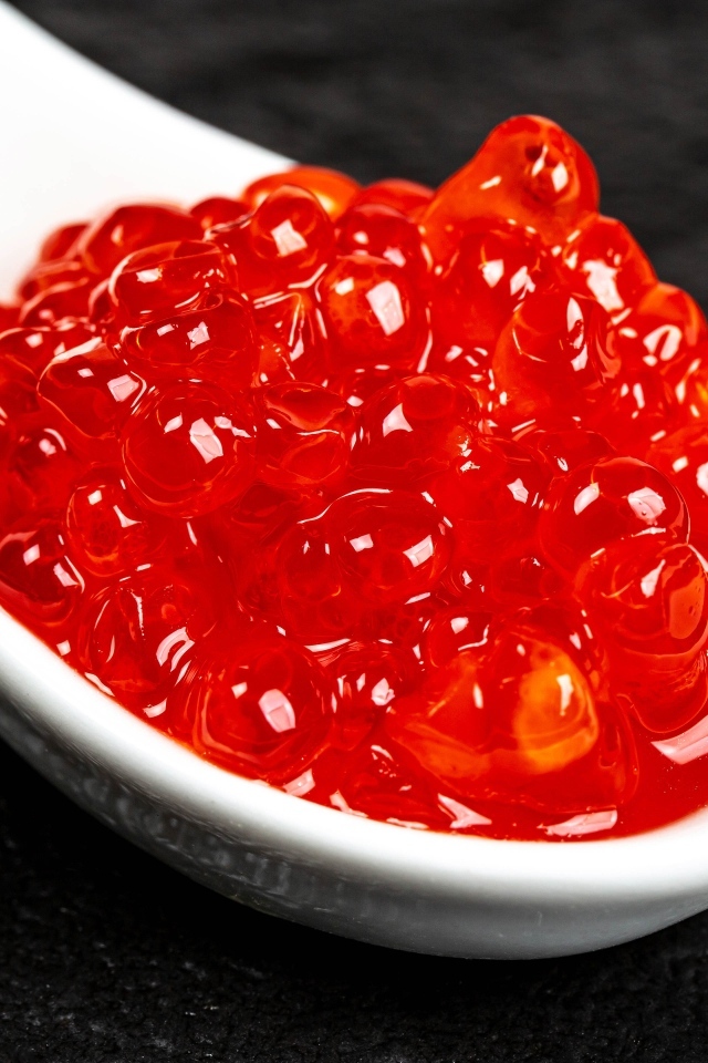 Красная икра на белой ложке крупным планом