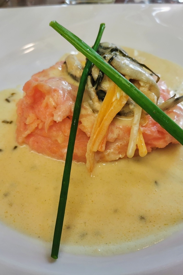 Красная рыба с соусом на тарелке с зеленым луком