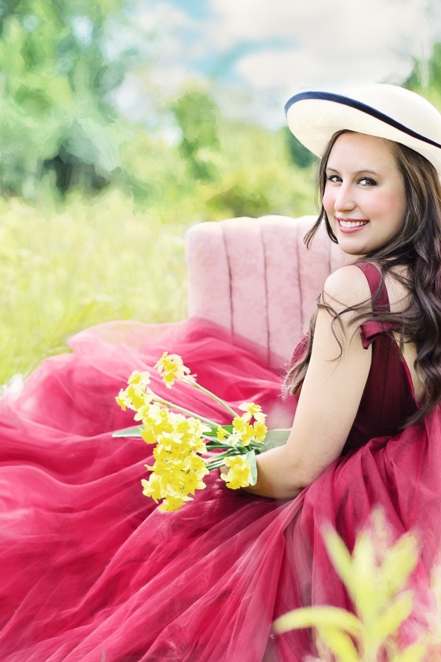 Красивая девушка в розовом платье сидит на кресле в траве