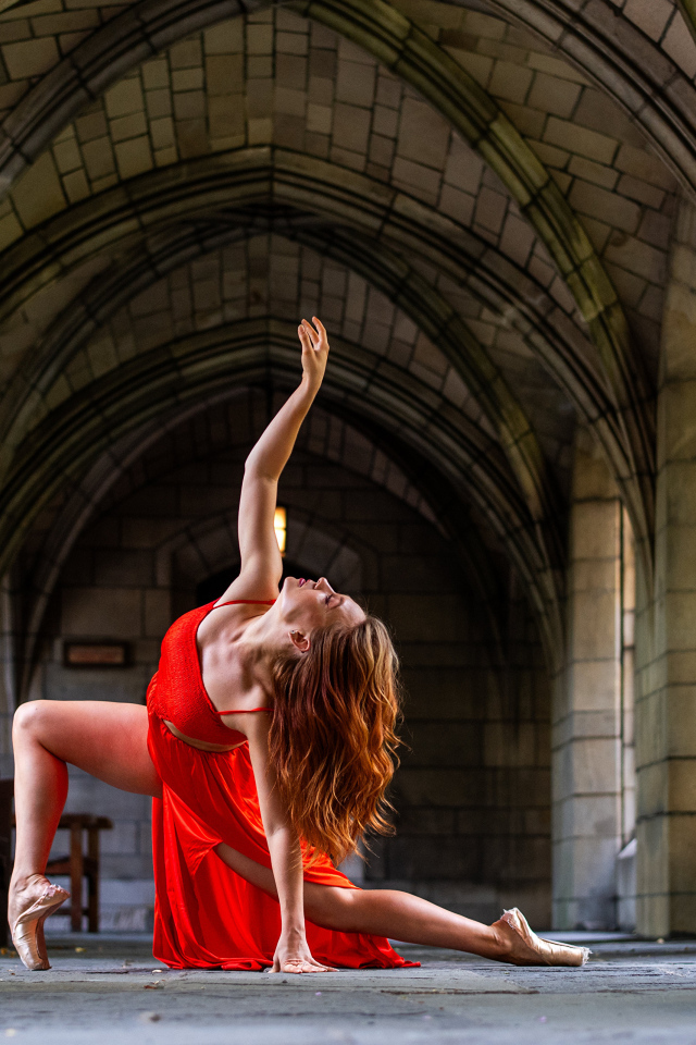 Девушка в красном наряде танцует в здании